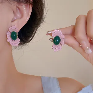 Detaillierte Nahaufnahme von Vintage-Ohrringen mit rosa Blüten und grünem Stein