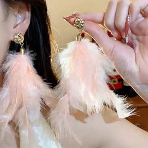 Detail of elegant pink feather tassel earrings with golden hammered metal studs.