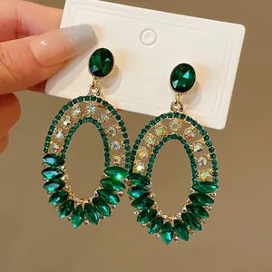 Close-up of vintage oversized green crystal oval hoop earrings with gold-tone setting