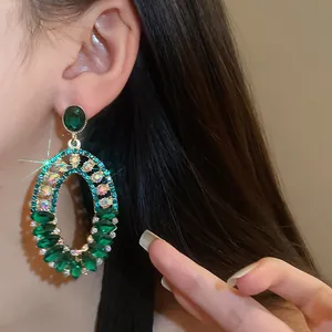 Detailed view of luxury vintage green rhinestone oval drop earrings on model's ear