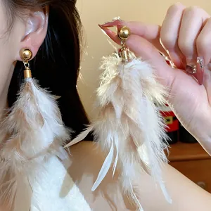 Detailed close-up view of elegant long cream feather tassel earrings on a model