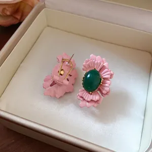 Detailansicht der filigranen rosa Blütenblätter und des grünen ovalen Steins der Ohrringe