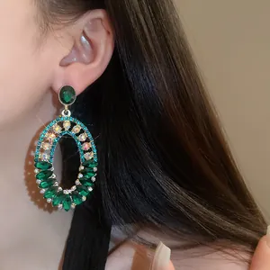 Detailed macro view of vintage oval emerald green rhinestone earrings worn on the ear