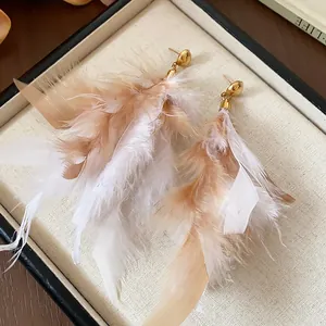 Detail view of elegant feather tassel earrings with gold studs and soft textures
