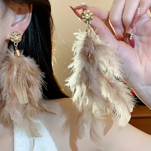 Detail shot of elegant feather tassel earrings with golden studs on a model.