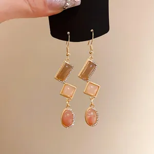 Detailed view of vintage geometric drop earrings with amber stones and rhinestones