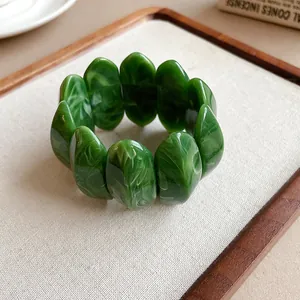 Vista dettagliata della texture marmorizzata verde di un bracciale elastico ovale in acrilico