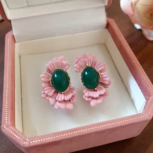 Nahaufnahme der rosa Blumen-Ohrstecker mit grünem ovalem Stein in einer Schmuckschatulle