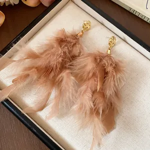 Detailed view of fluffy light brown feather tassel earrings in a box.
