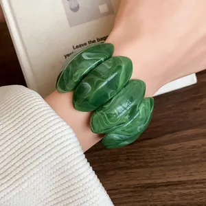 Primo piano dettagliato che mostra la trama marmorizzata verde del bracciale acrilico