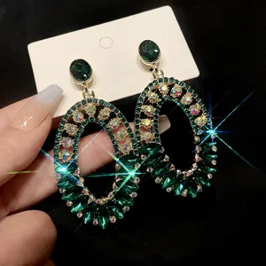 Close-up macro detail of vintage oval earrings with emerald green stones and rhinestones