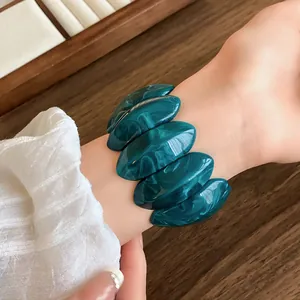 Primo piano dettagliato di un bracciale ovale in acrilico marmorizzato verde al polso