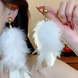 Detailed macro view of elegant white feather tassel earrings with refined golden beads