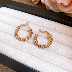 Boucles d'oreilles créoles dorées minimalistes avec texture irrégulière sur un plateau