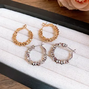 Gros plan de boucles d'oreilles créoles dorées et argentées sur un plateau à bijoux.