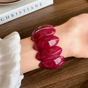 Dettaglio ravvicinato di un braccialetto in acrilico bordeaux effetto marmo