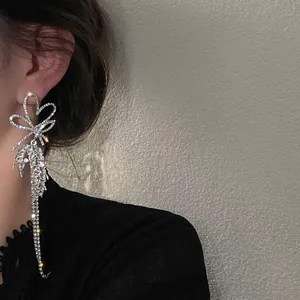 Macro detail view of elegant long sparkling bow-knot earrings with rhinestone tassels.