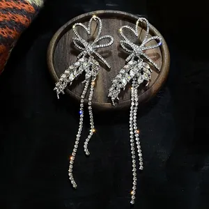 Detailed view of silver bow earrings with sparkling crystal tassels and wheat ear design.