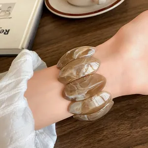 Vista dettagliata di un bracciale in acrilico marmorizzato marrone indossato al polso