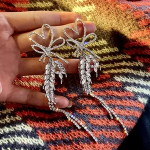 Detailed macro shot of silver heart and bow earrings with long sparkling crystal tassels