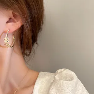 Close-up of elegant gold-plated flower hoop earrings with sparkly pavé rhinestones