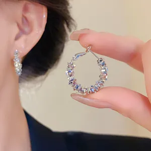 Gros plan de créoles argentées irrégulières avec un design texturé porté sur l'oreille du modèle
