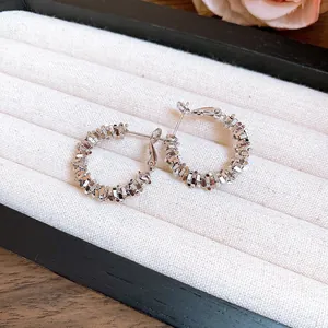 Gros plan de boucles d'oreilles créoles texturées en argent irrégulier dans un coffret