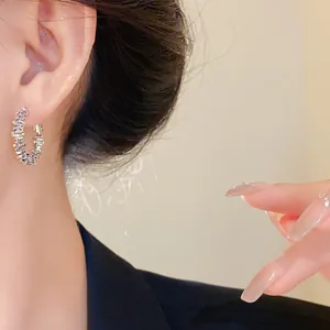 Gros plan détaillé d'élégantes créoles argentées irrégulières portées par un mannequin