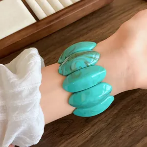 Vista dettagliata di perle acriliche ovali turchese marmorizzato su un ampio bracciale retrò
