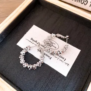 Détail de créoles en argent avec texture facettée irrégulière pour femme sur fond noir