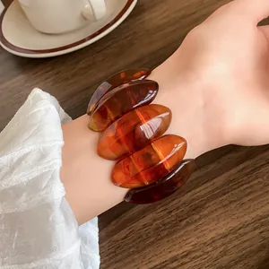 Primo piano di bracciale in acrilico ambra con design ovale su polso in stile retrò