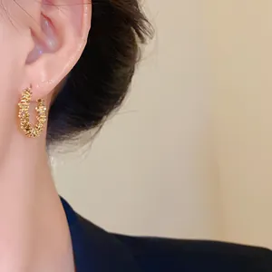 Gros plan de créoles dorées à texture irrégulière portées à l'oreille