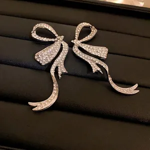Luxurious silver bow tassel earrings with pavé rhinestones on black jewelry tray
