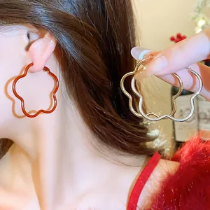 Close-up of elegant flower-shaped hoop earrings in vibrant red, gold, and silver
