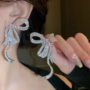 Close-up of elegant rhinestone bow earrings with silver needles in a luxurious style.