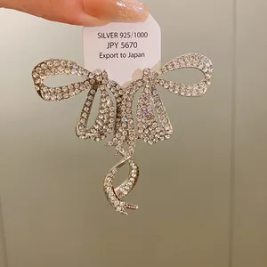 Close-up of sparkling rhinestone bow earrings with 925 silver tag detail