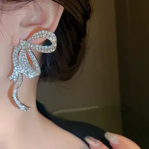Detail shot of a sparkling rhinestone bow earring with long flowing tassels.