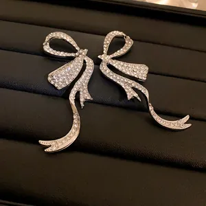 Detailed macro view of elegant silver bow-knot earrings encrusted with shimmering rhinestones