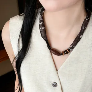 Detailopname van vintage stoffen kralenketting met houten accenten op een vrouwelijk model