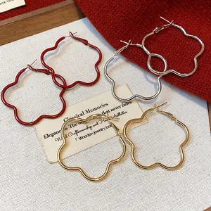 Macro detail view of elegant Korean style floral hoop earrings in red, gold, and silver tones.