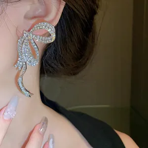 Detailed macro view of a luxury sparkling rhinestone bow tassel earring on a model ear