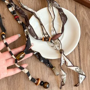 Vintage boheemse stoffen lintketting met houten en acryl kralen in aardetinten