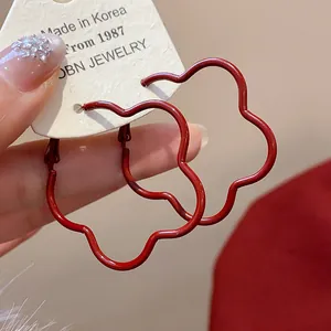 Close-up of dark red flower-shaped wave hoop earrings with Korean minimalist design