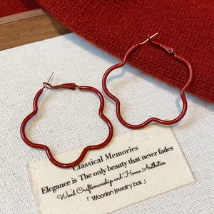 Detail view of red flower-shaped hoop earrings with elegant matte finish on canvas