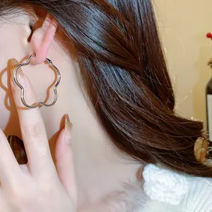 Detailed view of elegant silver-toned flower-shaped hoop earrings worn on an ear