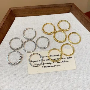 Anelli impilabili placcati oro e argento con zirconi in un vassoio di legno