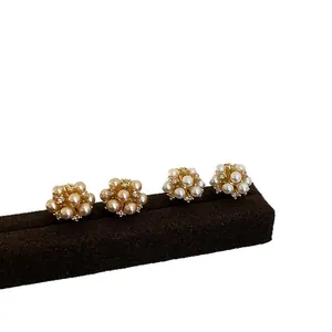 Elegant pearl cluster stud earrings with sparkling crystal accents on a dark stand