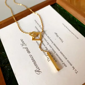 Close-up of gold stainless steel geometric square and bar pendant necklace on a card.