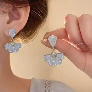 Dettaglio degli eleganti orecchini a fiore bianchi in smalto in stile Mori chic