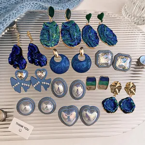 Detailed view of vintage blue and green crystal earrings set on a textured glass tray